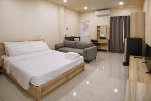 a bedroom with a bed and a couch and a television at วลัญชญ์ โฮเทล ศรีราชา in Ban Nong Chaeng