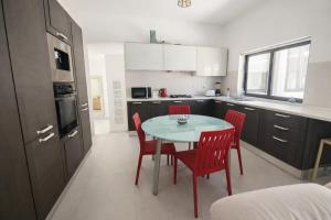 a kitchen with a table and red chairs in it at Modern Double Room in Peaceful Pembroke just Minutes away from St Julians in Pembroke