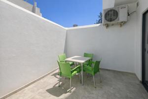 a table and green chairs on a patio at Modern Double Room in Peaceful Pembroke just Minutes away from St Julians in Pembroke