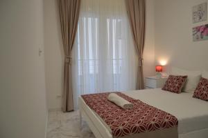 a bedroom with a bed with a red and white comforter at Yeshill Deluxe Apartment in Budva