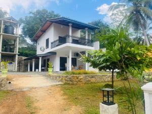 a white house with a balcony and a yard at The villa Evans in Pitiduwa