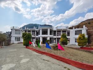 a white building with flags in front of it at Rajvin Heavens Resort in Bhīm Tāl