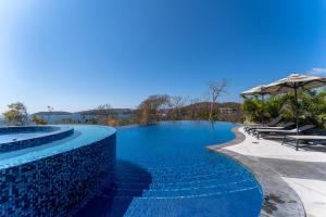 a swimming pool with blue water and umbrellas at 3082 - Paradise Cove 3A Manzanillo in Tangolunda