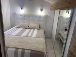 a small bedroom with a bed and a mirror at Le petit château de sable in Valras-Plage
