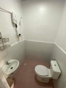 a white bathroom with a toilet and a sink at JEHH8 Guest House in Siquijor