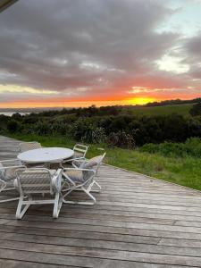 a table and chairs on a deck with a sunset at Leigh Backpackers in Leigh