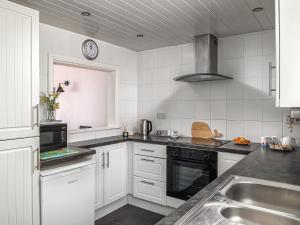 a white kitchen with a sink and a stove at Harbour View in Cemaes Bay