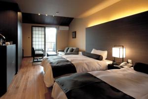 ein Hotelzimmer mit 3 Betten und einem Sofa in der Unterkunft Hotel Morinokaze Tateyama‎ in Toyama