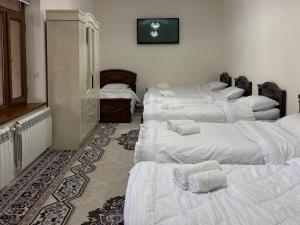 a room with four beds with towels on them at Hostel Azizjon in Samarkand