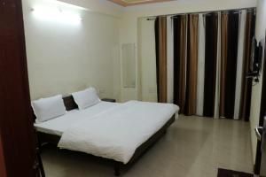 a bedroom with a bed with white sheets and pillows at The Gopi Dham Hotel in Haridwār