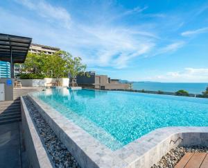 a swimming pool with the ocean in the background at Bluphere Residence by Prop Hopper in Na Jomtien