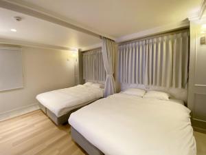 two beds in a small room with white sheets at precious days inn in Fukuoka
