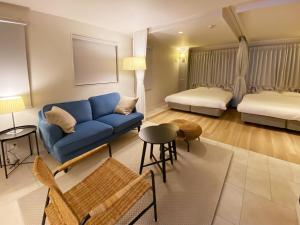 a living room with a blue couch and two beds at precious days inn in Fukuoka