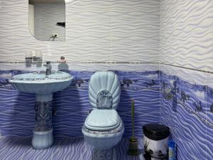 a blue and white bathroom with a toilet and a sink at Hostel Azizjon in Samarkand