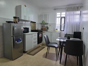 a kitchen with a table and a stainless steel refrigerator at Jay Homes -Ultra Modern Naivegas Apartments in Naivasha