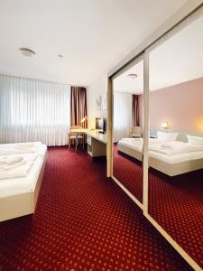 a hotel room with two beds and a mirror at WAGNERS Sporthotel Oberhof in Oberhof +31 photos