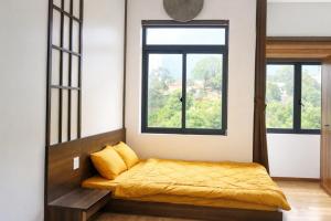 a bedroom with a bed and two windows at B'lao Eco Lodge in Bảo Lộc
