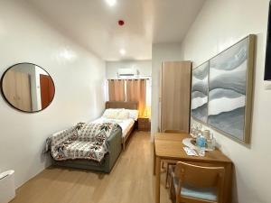 a bedroom with a bed and a table and a mirror at E&J Solace Studio Mactan Bayanihan Flats 2 in Maribago