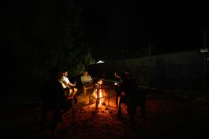 a group of people sitting around a fire at night at Skybz Resort - Mankulam in Viripara +60 photos