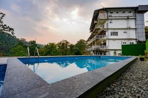 a swimming pool in front of a building at Skybz Resort - Mankulam in Viripara
