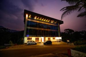 two cars parked in front of a building at night at Skybz Resort - Mankulam in Viripara