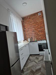 a kitchen with white appliances and a brick wall at apartament in Skarżysko-Kamienna