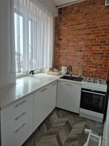 a kitchen with white cabinets and a brick wall at apartament in Skarżysko-Kamienna