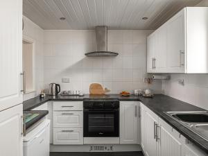 a kitchen with white cabinets and a black oven at Harbour View in Cemaes Bay