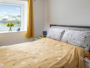 a bedroom with a bed and a window with flowers at Harbour View in Cemaes Bay