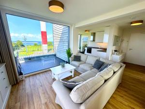 a living room with a white couch and a large window at Penthouse Seeblick am Leuchtturm in Fehmarn