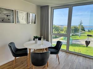 a dining room with a table and chairs and a window at Penthouse Seeblick am Leuchtturm in Fehmarn +9 photos