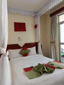 a bedroom with a white bed with red and green pillows at Raya hotel Nyali Mombasa in Mombasa
