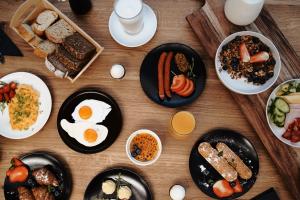 a wooden table with plates of breakfast foods and eggs at Baltic Jet Luxury Aparthotel in Ustronie Morskie
