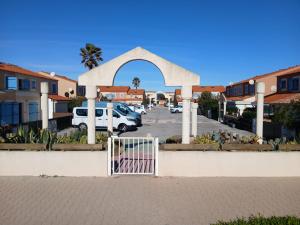 a gate in front of a parking lot with cars at Maisonnette n 43" La Tortue " in Frontignan
