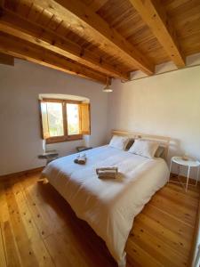 a bedroom with a large white bed with wooden floors at Ca La Pausa in Alpens