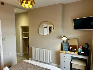 a bedroom with a bed and a mirror and a tv at Hotel No5, Beachfront with Free Private Car Park in Llandudno