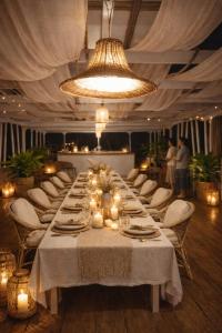 a long dining table with white chairs and a chandelier at Amber Dahabiya in Luxor