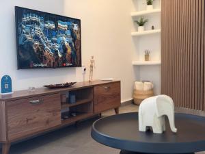 a living room with a tv and a table at White Swallow Suite Santorini in Vourvoúlos