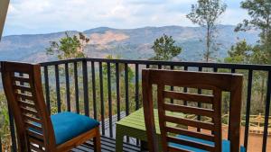 a balcony with two chairs and a view of mountains at Idukki Nook in Idukki