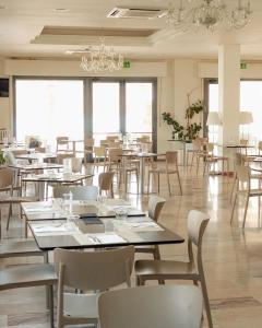 a dining room with tables and chairs and windows at GFH - Hotel Sole Resort in Marotta