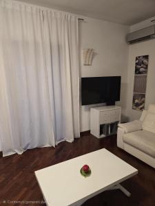 a living room with a white couch and a tv at Bis Jolly 1 in Cosenza
