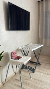 a table and a chair with a tv on a wall at Suites Appartement Midelt in Midelt