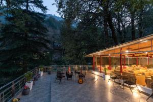 a person sitting on a balcony with tables and chairs at Moustache Hostel Nainital in Nainital