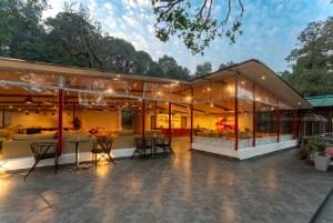 a house with glass walls and tables and chairs at Moustache Hostel Nainital in Nainital