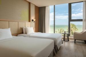 two beds in a hotel room with a view of the ocean at Navada Beach Hotel in Nha Trang