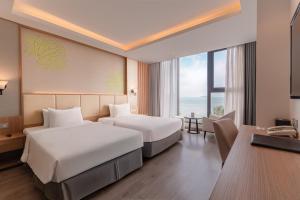 a hotel room with two beds and a desk at Navada Beach Hotel in Nha Trang