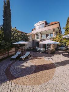 a patio with two chairs and umbrellas in front of a building at Villa Alenor – Sea View & Beach Access in Nesebar