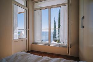 a bedroom with windows and a bed with a view at Villa Alenor – Sea View & Beach Access in Nesebar