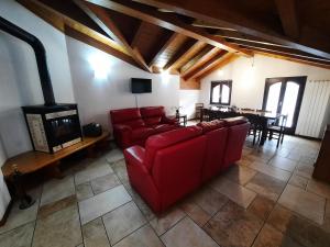 a living room with a red couch and a fireplace at Casa Vacanza Dal Contadino in Corteno Golgi