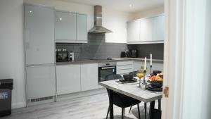 a kitchen with white cabinets and a table with glasses of wine at The Emerald Residence - Leicester - City Centre, Sofa Bed, Parking, Free WiFi, Netflix in Leicester
